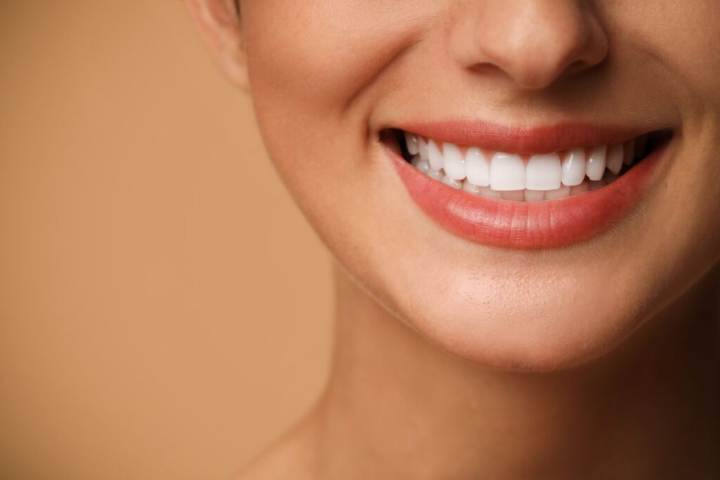 Close-up of a smiling mouth showing bright white teeth and pink lips.